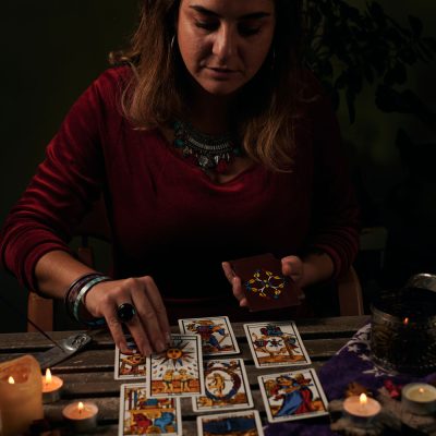 pythoness-reads-tarot-cards-on-a-table-with-candle-2022-03-29-23-44-16-utc